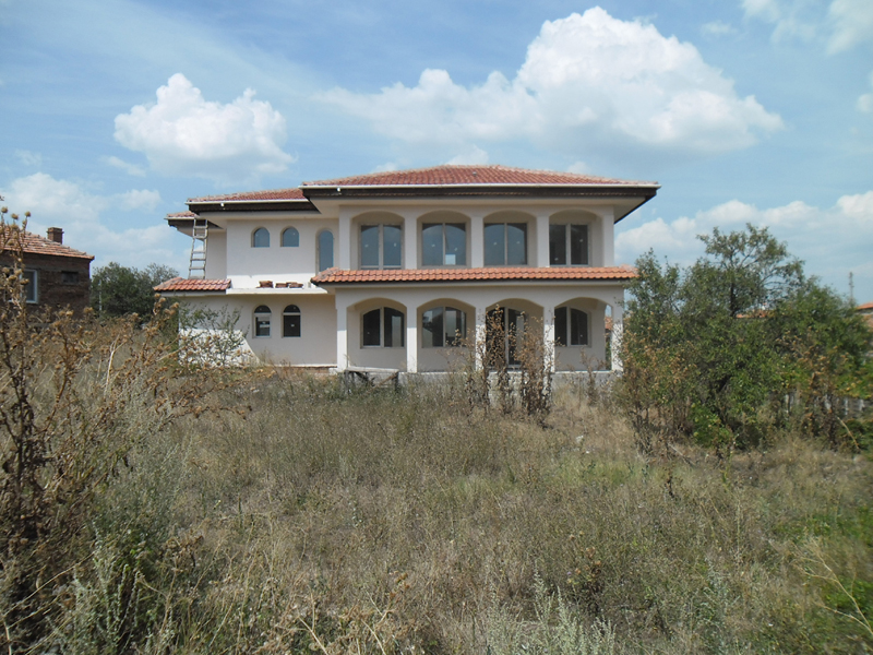 Back of house with overgrown weeds